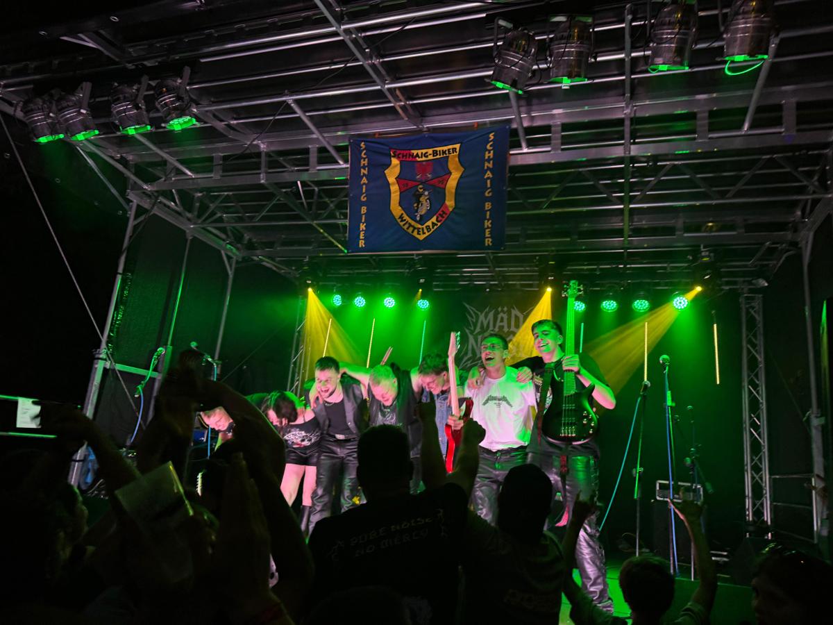 Die Band feiert gemeinsam auf der Bühne im grünen Licht